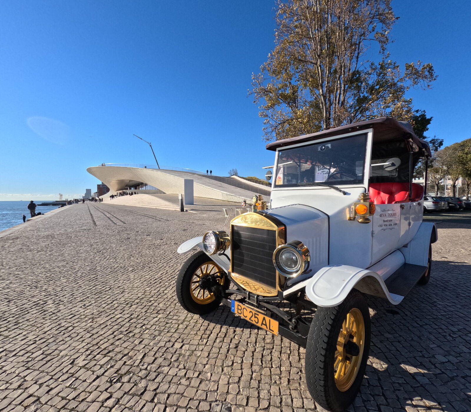 A white vintage tuktuk on the Tagus waterfront