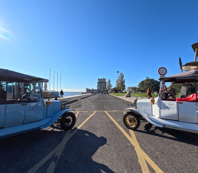 Two vintage tuktuks with Belém Tower in the distance